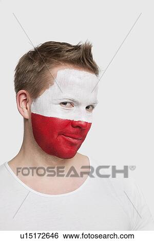 Stock Photograph - Portrait of young man with Polish flag painted on face smiling against white background. Fotosearch