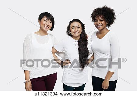 Picture - Portrait of young multi-ethnic female friends in casuals smiling over white background. Fotosearch
