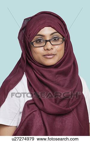 Stock Photo - Portrait of young Muslim woman in traditional clothing against blue background. Fotosearch