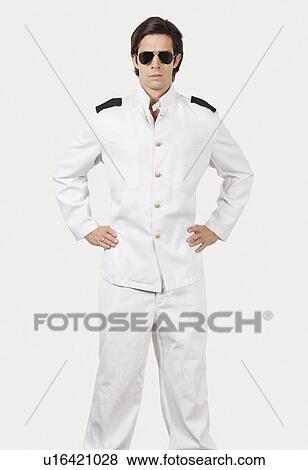 Stock Photo - Portrait of young navy officer standing against gray background. Fotosearch