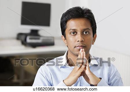 Portrait of young pensive businessman with hands clasped sitting at office View Large Photo Image Stock Photo - Portrait of young pensive businessman with hands clasped sitting at office. Fotosearch