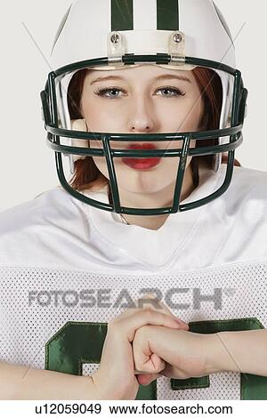 Stock Photo - Portrait of young woman in football uniform against gray background. Fotosearch