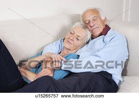 Romantic senior couple with arms around relaxing on sofa at home View Large Photo Image Stock Photo - Romantic senior couple with arms around relaxing on sofa at home. Fotosearch