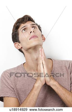 Sad young man with hands clasped praying over white background View Large Photo Image Stock Photo - Sad young man with hands clasped praying over white background. Fotosearch