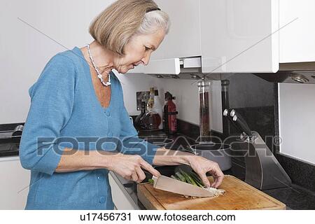 Senior woman chopping vegetables at kitchen counter View Large Photo Image Stock Image - Senior woman chopping vegetables at kitchen counter. Fotosearch