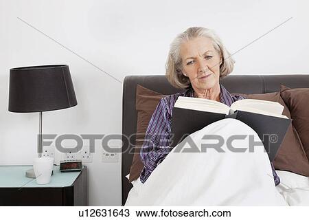 Senior woman reading book in bedroom at home View Large Photo Image Stock Image - Senior woman reading book in bedroom at home. Fotosearch
