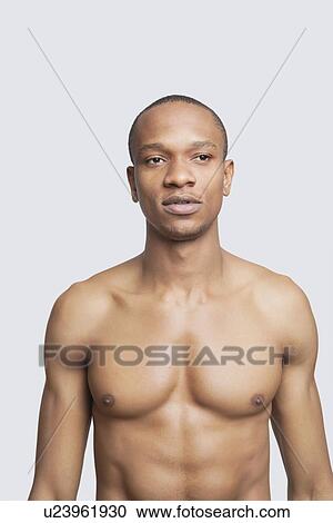 Shirtless young man standing against gray background View Large Photo Image Stock Image - Shirtless young man standing against gray background. Fotosearch