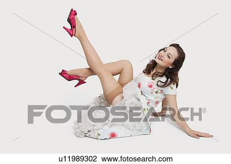 Studio portrait of beautiful young woman in dress sitting on floor with feet up View Large Photo Image Stock Image - Studio portrait of beautiful young woman in dress sitting on floor with feet up. Fotosearch