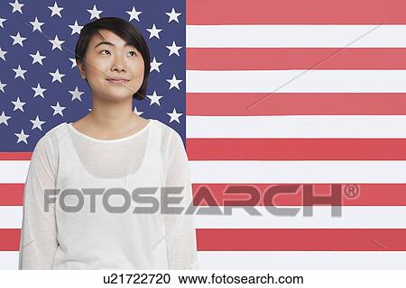 Thoughtful Asian woman looking away against American flag View Large Photo Image Stock Image - Thoughtful Asian woman looking away against American flag. Fotosearch