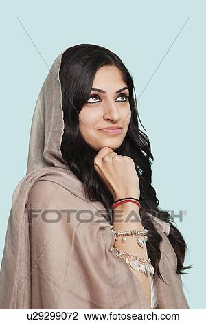 Thoughtful young Asian woman in traditional clothing standing against blue background View Large Photo Image Stock Image - Thoughtful young Asian woman in traditional clothing standing against blue background. Fotosearch