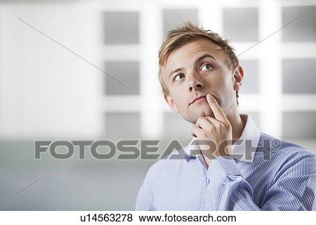 Thoughtful young Caucasian businessman at office View Large Photo Image Stock Photo - Thoughtful young Caucasian businessman at office. Fotosearch