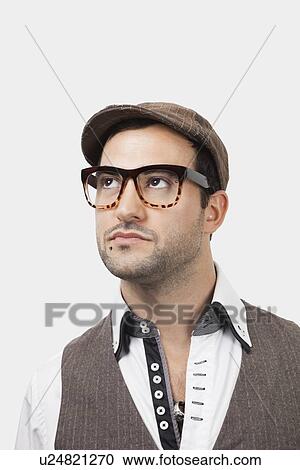 Stock Image - Thoughtful young Caucasian man in flat cap against white background. Fotosearch