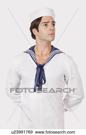 Stock Photo - Thoughtful young man in sailor's uniform looking away against gray background. Fotosearch