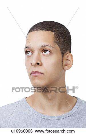 Stock Image - Thoughtful young man looking away against white background. Fotosearch