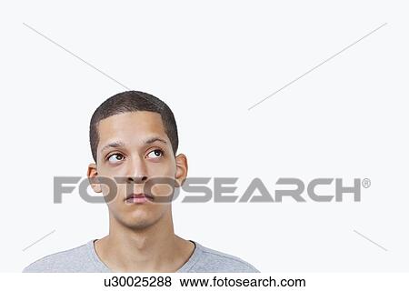 Thoughtful young mixed race man looking sideways against white background View Large Photo Image Stock Photo - Thoughtful young mixed race man looking sideways against white background. Fotosearch