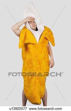 Stock Photo - Tired man in banana costume against gray background. Fotosearch