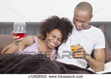 Young African American couple enjoying drinks together in bed View Large Photo Image Stock Image - Young African American couple enjoying drinks together in bed. Fotosearch