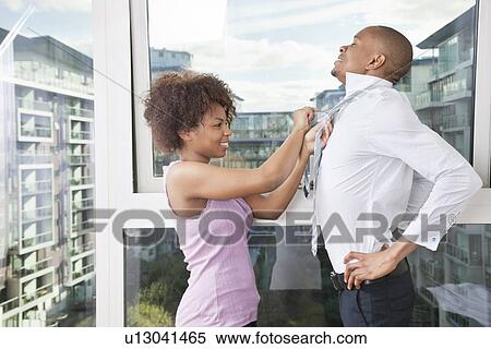 Stock Photography - Young African American woman adjusting man's tie. Fotosearch