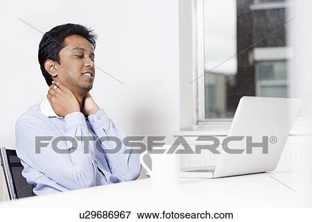 Young businessman looking at laptop in office View Large Photo Image Stock Photo - Young businessman looking at laptop in office. Fotosearch