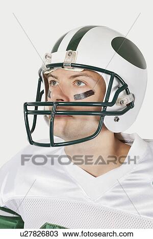 Young man in football uniform looking away against gray background View Large Photo Image Stock Image - Young man in football uniform looking away against gray background. Fotosearch