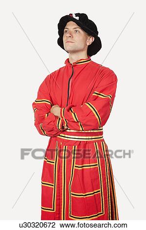 Stock Image - Young man in orange costume with arms crossed against gray background. Fotosearch