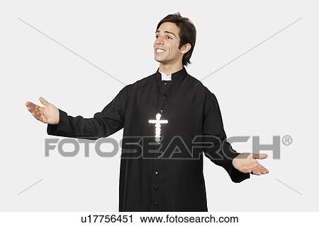Young man in priest costume gesturing against gray background View Large Photo Image Stock Image - Young man in priest costume gesturing against gray background. Fotosearch