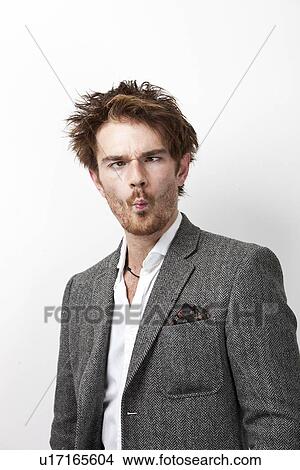Picture - Young man in suit making funny faces against white background. Fotosearch
