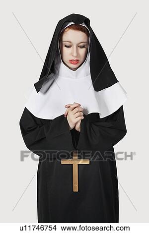 Young nun with cross praying against gray background View Large Photo Image Picture - Young nun with cross praying against gray background. Fotosearch