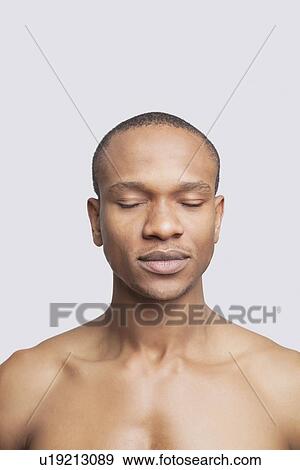 Young shirtless man with eyes closed against gray background View Large Photo Image Stock Photo - Young shirtless man with eyes closed against gray background. Fotosearch