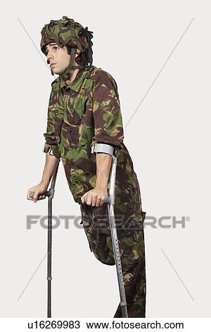Young soldier holding crutches against gray background View Large Photo Image Stock Image - Young soldier holding crutches against gray background. Fotosearch