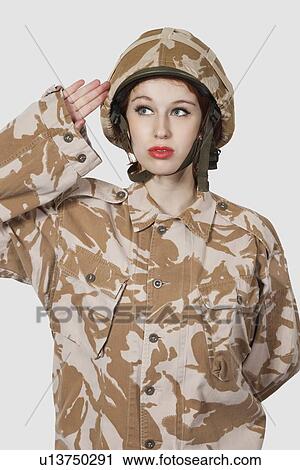 Young woman in military uniform saluting against gray background View Large Photo Image Stock Image - Young woman in military uniform saluting against gray background. Fotosearch