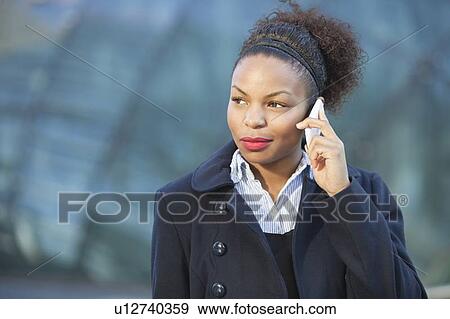 Stock Photo - Beautiful young woman in formals using mobile phone. Fotosearch
