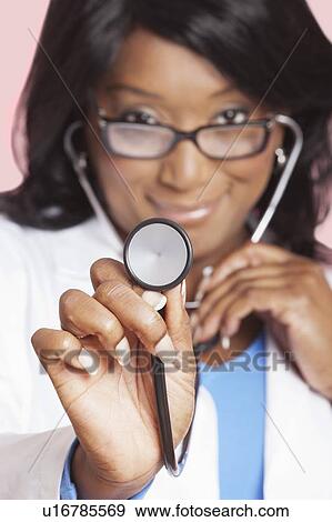 Close-up of female doctor holding stethoscope over pink background View Large Photo Image Stock Photo - Close-up of female doctor holding stethoscope over pink background. Fotosearch