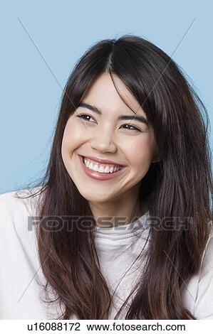 Close-up of happy young woman looking away over blue background View Large Photo Image Stock Image - Close-up of happy young woman looking away over blue background. Fotosearch
