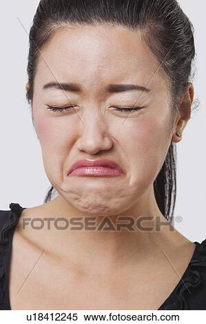 Stock Photography - Close-up of young Chinese woman crying over white background. Fotosearch