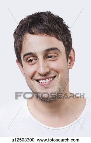 Close-up of young man smiling over white background View Large Photo Image Stock Image - Close-up of young man smiling over white background. Fotosearch