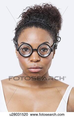 Stock Image - Close-up portrait of African American young woman wearing novelty glasses over white background. Fotosearch