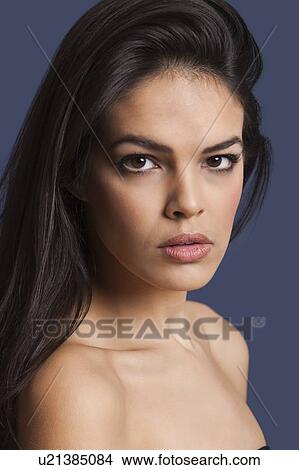 Close-up portrait of beautiful young woman over blue background View Large Photo Image Picture - Close-up portrait of beautiful young woman over blue background. Fotosearch