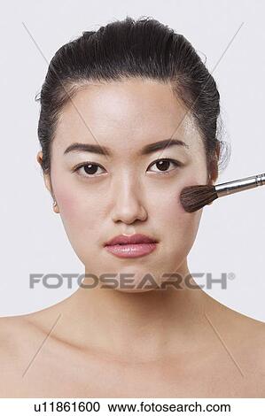Close-up portrait of young woman applying blush over white background View Large Photo Image Stock Image - Close-up portrait of young woman applying blush over white background. Fotosearch