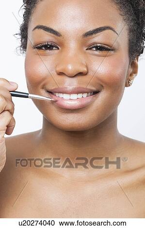 Close-up portrait of young woman applying lip gloss with brush View Large Photo Image Stock Image - Close-up portrait of young woman applying lip gloss with brush. Fotosearch