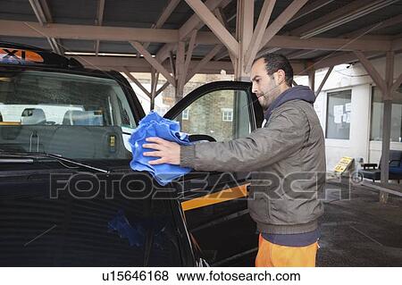 Employee wiping vehicle window in car wash View Large Photo Image Stock Photo - Employee wiping vehicle window in car wash. Fotosearch