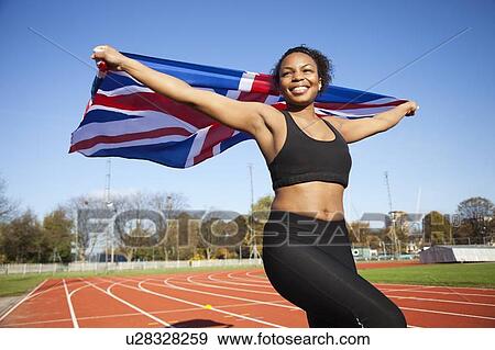 Happy young female athlete holding up British flag on running track View Large Photo Image Stock Photo - Happy young female athlete holding up British flag on running track. Fotosearch