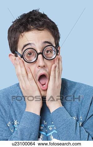 Nerdy man wearing novelty glasses with mouth open in surprise over blue background View Large Photo Image Picture - Nerdy man wearing novelty glasses with mouth open in surprise over blue background. Fotosearch