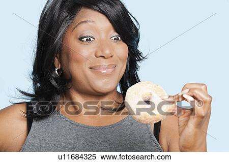 Overweight mixed race woman eating donut over blue background View Large Photo Image Stock Photography - Overweight mixed race woman eating donut over blue background. Fotosearch
