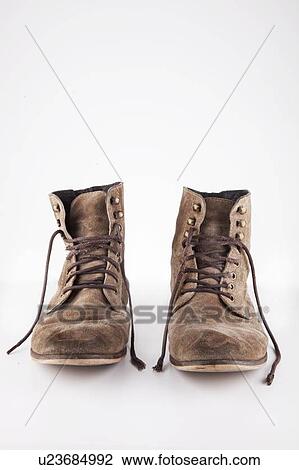 Stock Image - Pair of vintage brown boots with untied laces over white background. Fotosearch