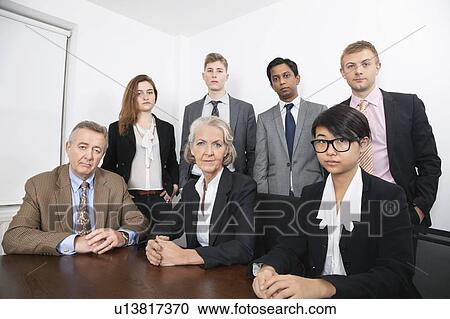 Stock Image - Portrait of confident multiethnic business group at desk in office. Fotosearch