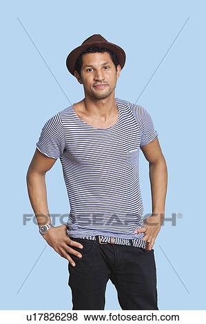 Portrait of cool young man with hands on hips over blue background View Large Photo Image Stock Photo - Portrait of cool young man with hands on hips over blue background. Fotosearch