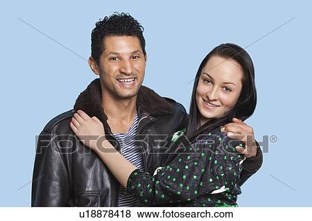 Portrait of couple with arms around smiling against blue background View Large Photo Image Stock Photo - Portrait of couple with arms around smiling against blue background. Fotosearch
