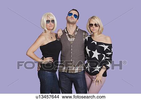 Picture - Portrait of man with two beautiful women over purple background. Fotosearch