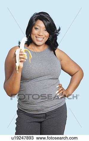Portrait of mixed race woman holding banana over blue background View Large Photo Image Stock Image - Portrait of mixed race woman holding banana over blue background. Fotosearch